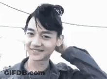 Young Man With Bun Smiling Touching Head GIF