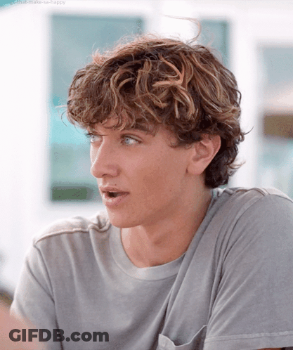 Young Man With Curly Hair In Gray Shirt GIF