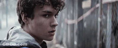 Young Man With Curly Hair In Grey Hoodie Looking At Camera GIF