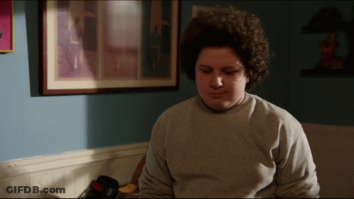 Young Man With Curly Hair In Grey Sweatshirt GIF