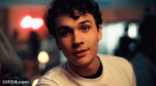 Young Man With Curly Hair Looking At Camera Blurry Background GIF