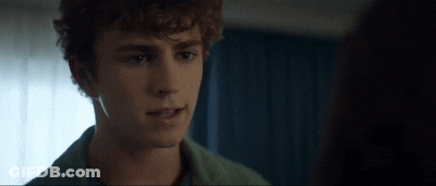 Young Man With Curly Hair Looking At Woman In Dark Room GIF