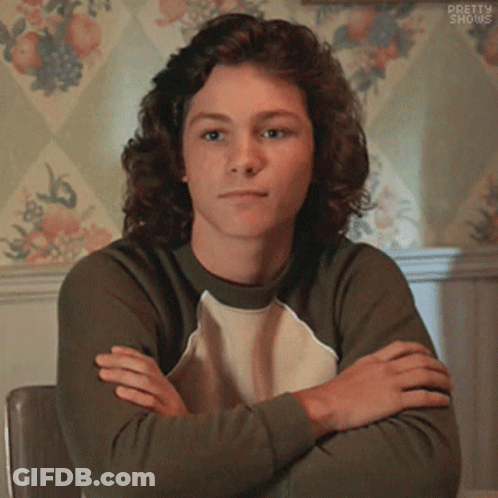 Young Man With Curly Hair Sitting Crossed Arms GIF