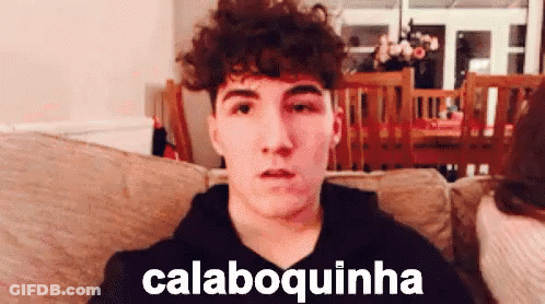 Young Man With Curly Hair Sitting On Couch Saying Calaboquinha GIF