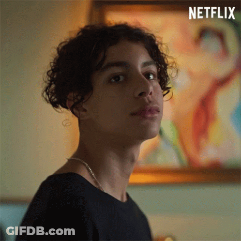 Young Man With Curly Hair Standing In Front Of Painting GIF