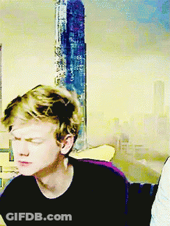 Young Man With Eyes Closed Sitting In Front Of Yellow Wall GIF