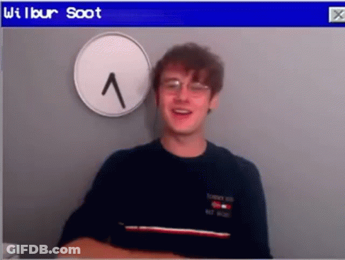 Young Man With Glasses Beside Clock GIF