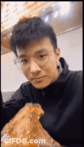 Young Man With Glasses Eating Large Piece Of Food GIF