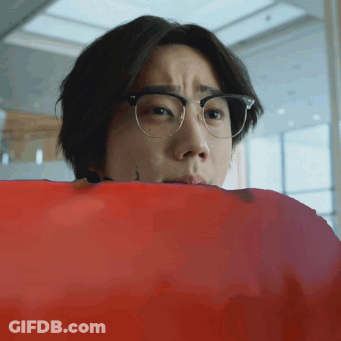 Young Man With Glasses Looking Over Red Blanket GIF