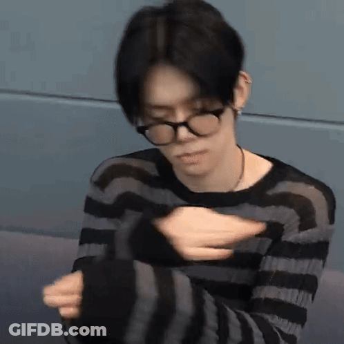 Young Man With Glasses Sitting In Striped Sweater GIF