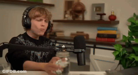 Young Man With Headphones Sitting At Microphone Holding Jar GIF