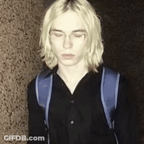 Young Man With Long Blonde Hair And Blue Backpack GIF