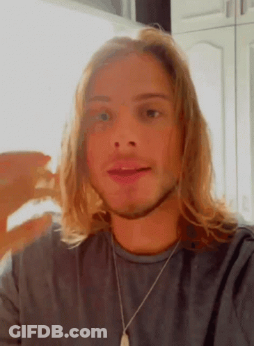Young Man With Long Blonde Hair In Gray Shirt And Necklace GIF