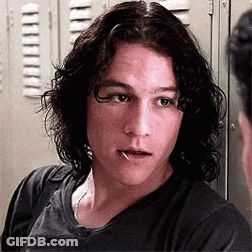 Young Man With Long Curly Hair Standing In Front Of Lockers GIF