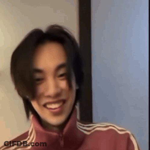 Young Man With Long Hair In Red Adidas Jacket Smiling GIF
