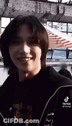 Young Man With Long Hair Smiling In Black Jacket GIF