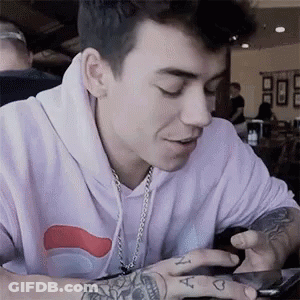 Young Man With Tattoos Looking At Phone GIF