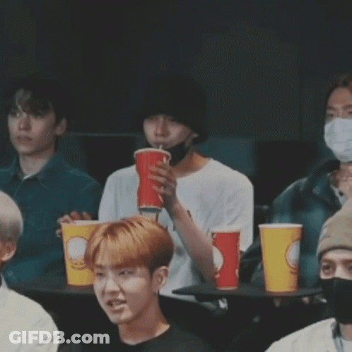 Young Men At Table With Cups, One Covering Mouth GIF