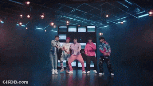 Young Men Dancing On Stage In Front Of TV Wall GIF