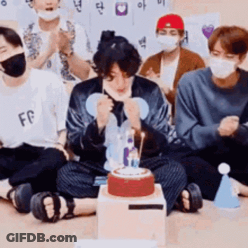 Young Men In Face Masks Sitting Around Cake GIF