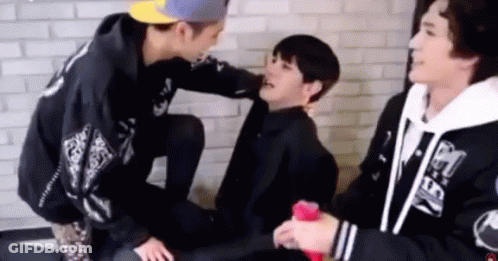 Young Men Sitting And Talking In Front Of Brick Wall GIF