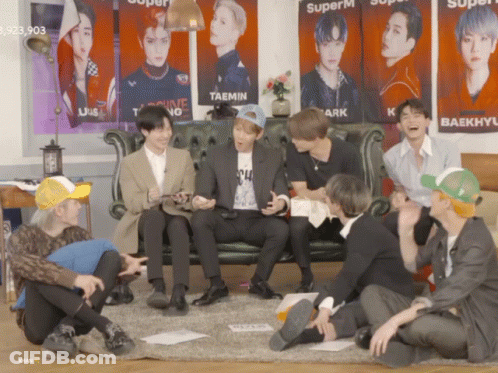 Young Men Sitting On Floor In Front Of Couch With Superm Posters GIF