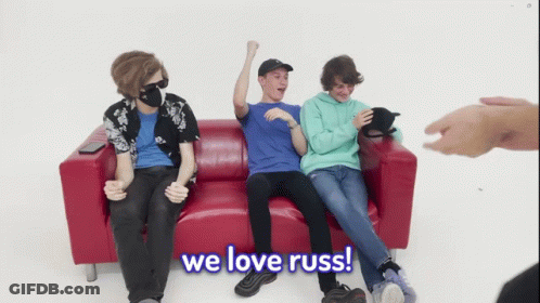 Young Men Sitting On Red Couch One Wearing Mask GIF