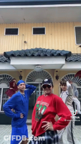 Young Men Standing In Front Of Yellow Building GIF