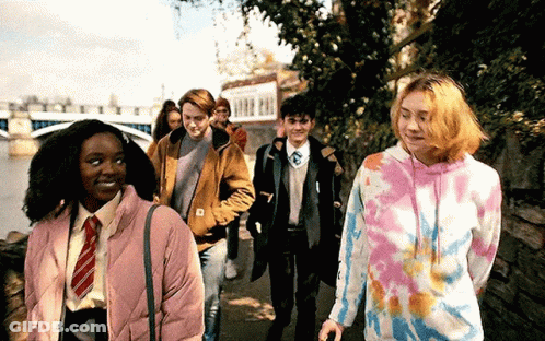 Young People Walking Down Sidewalk Next To River GIF