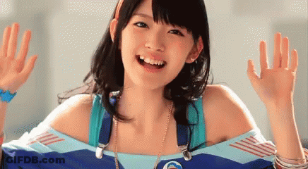Young Woman In Blue Shirt Smiling And Waving GIF