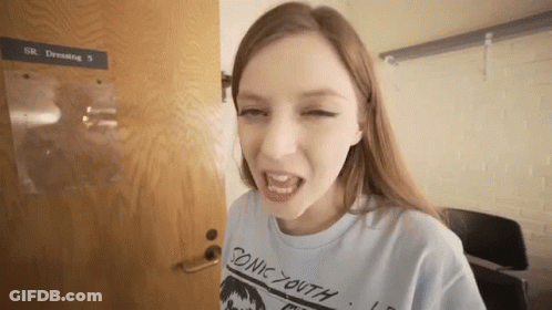 Young Woman In Blue Sonic Youth Shirt At Door GIF