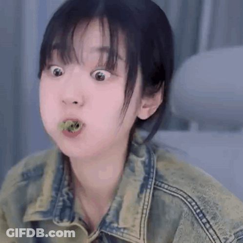 Young Woman In Denim Jacket Making Funny Face Eating Green Leaf GIF