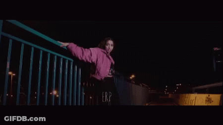 Young Woman In Pink Jacket On Bridge At Night GIF
