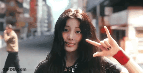 Young Woman Making Peace Sign On City Street GIF