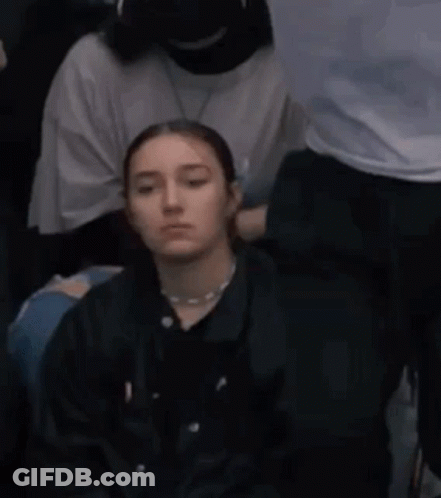 Young Woman Sitting In Crowd GIF