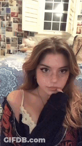 Young Woman Sitting On Bed By Window GIF