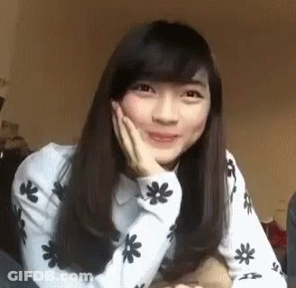 Young Woman Sitting On Bed With Hand On Face GIF