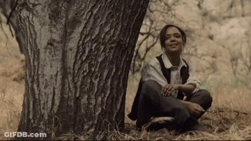 Young Woman Sitting Under Tree In Woods GIF