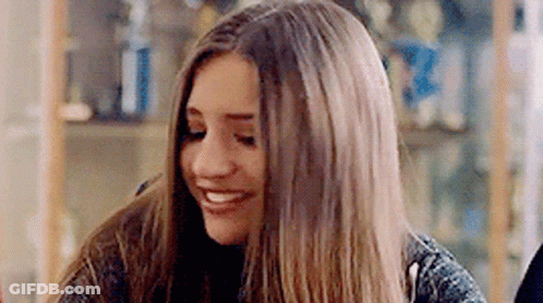 Young Woman With Long Hair Smiling At Table GIF