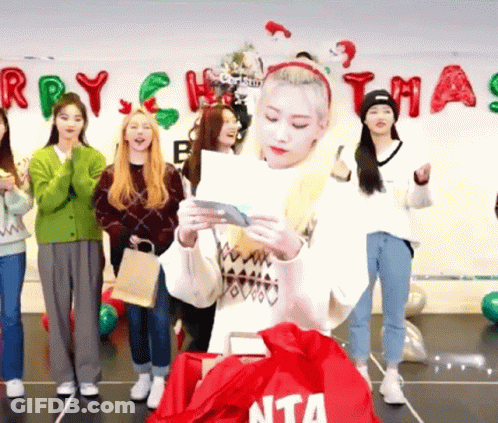Young Women Standing In Front Of Christmas Banner GIF