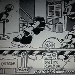 A meme-style GIF of Mickey Mouse holding a heart-shaped piece of Swiss cheese