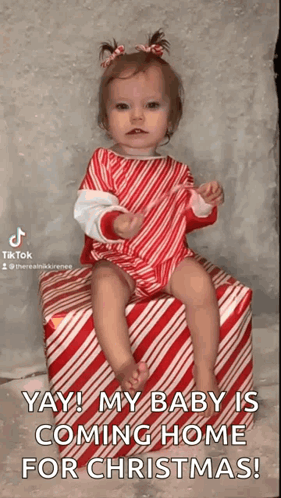 A Baby Girl Is Sitting On A Candy Cane Striped Box . GIF