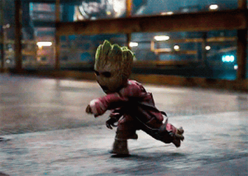 A Baby Groot Is Running Down A Street Wearing Sunglasses And A Red Jacket GIF