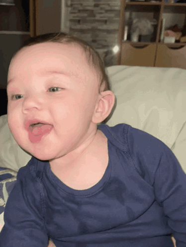 A Baby In A Blue Shirt Is Sticking Out Its Tongue GIF