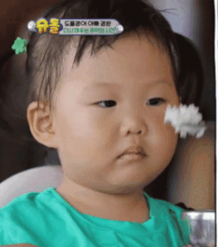 A Baby In A Green Shirt Is Eating Rice GIF