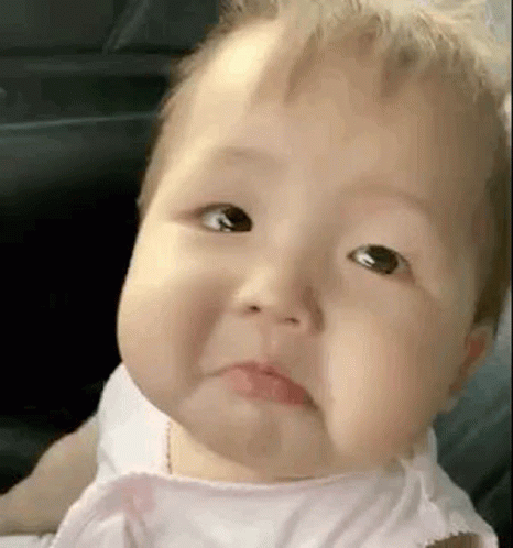 A Baby In A Pink Dress Is Making A Sad Face . GIF