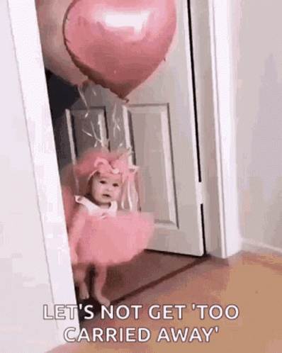 A Baby In A Pink Dress Is Standing In A Doorway With A Heart Shaped Balloon . GIF