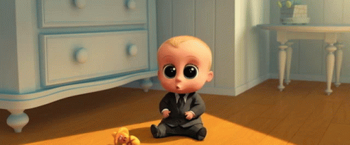 A Baby In A Suit And Tie Sits On The Floor Next To A Teddy Bear GIF