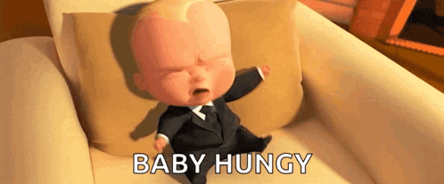 A Baby In A Suit Is Crying While Sitting On A Couch With The Words `` Baby Hungry '' . GIF
