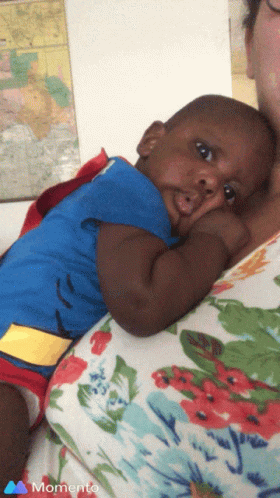 A Baby In A Superman Costume Is Being Held By A Woman In A Momento Photo GIF